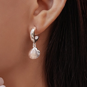 Close-up of elegant shell pendant earring worn on ear with high quality metallic finish