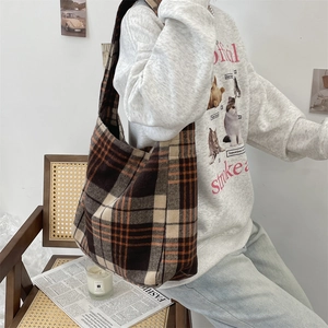 Close-up of high-capacity plaid canvas messenger bag with classic brown tartan texture