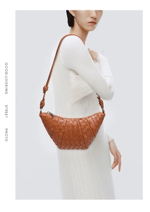 Detail of brown hand-woven leather croissant shoulder bag showing premium texture