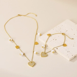 Detail of gold heart pendant necklace and bracelet set with pearls and rhinestones