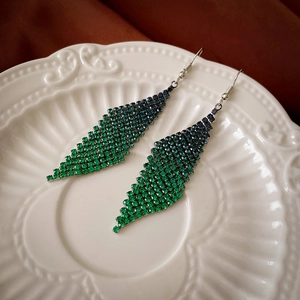 Détail de boucles d'oreilles géométriques à franges avec strass dégradés bleu et vert