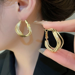 Detail shot of golden irregular geometric twisted earrings with textured metallic finish