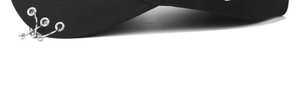 Detailed close-up of three silver metal rings and bead pendant on black baseball cap brim