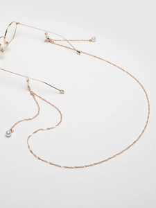Detailed view of golden metal eyewear chain featuring white pearls and silicone loops