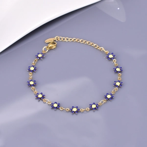 Gros plan détaillé d'un bracelet chaîne doré orné de marguerites en émail bleu et jaune
