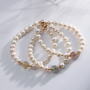Detailed macro view of three baroque pearl bracelets with colorful natural stone accents