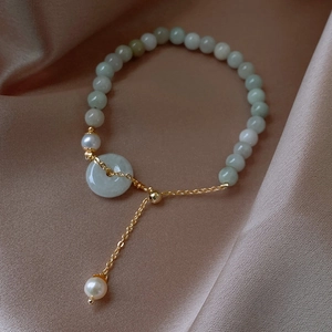 Detail of elegant Chinese jade bead bracelet with white pearl and gold metal chain