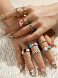 Close-up of vibrant 18k gold plated enamel flower and striped rings on female hands