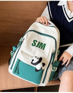 Close-up of green and white vintage backpack with panda plush charm held by a model