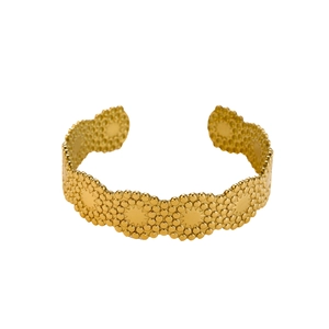 Detail of gold open cuff bracelet featuring wavy edges and embossed star patterns