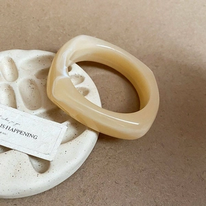 Makroaufnahme: Cremefarbener Acrylring in Ovalform mit Marmortextur auf Keramiktablett