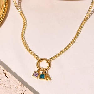 Detail of 18K gold plated necklace featuring blue and purple square gems and number 4 charm
