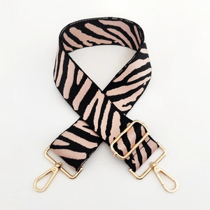Macro detail of zebra print bag strap with pink base and polished gold metal hooks