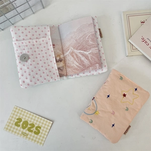 Close-up of star embroidery detail on pink fabric passport cover with woven brand label