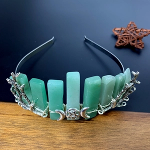 Silver crystal bridal crown with green stones and moon symbols on a rustic wooden background