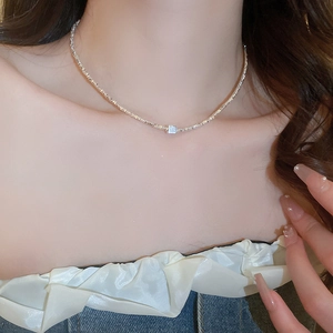 Close-up of a silver cube pendant necklace worn on a woman's neck for a minimalist look