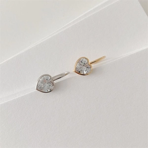 Close-up of gold and silver heart stud earrings with sparkling cubic zirconia stones