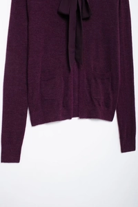 Détail d'un cardigan en maille violet foncé avec col à nouer élégant et texture douce