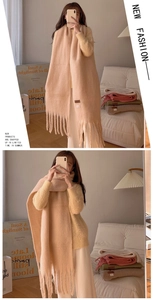 Detail of cream macaron knitted scarf with soft cashmere-like texture and tassel edges