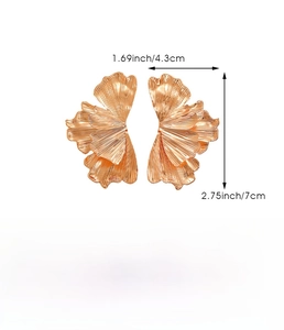 Macro detail of gold-finish leaf earrings with irregular wrinkled texture and iron material specs