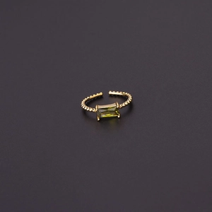 Detailed macro of a gold beaded ring with emerald-cut green cubic zirconia stone