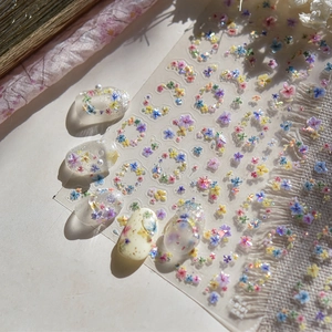 Macro detail of embossed floral nail art stickers with glitter finish on manicured tips