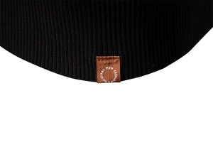 Detail of black knitted sweater hem featuring a brown rectangular leather brand patch