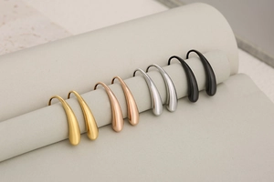 Detail of four teardrop earrings in gold, silver, rose gold, and matte black finish