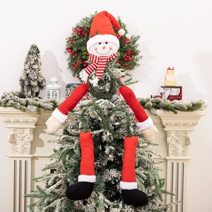 Close-up of a plush snowman topper with red arms hugging a snowy Christmas tree branch