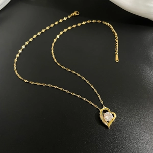 Collana con pendente a cuore dorato e cristalli luminosi su uno sfondo nero opaco