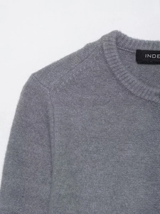 Dettaglio maglione in maglia grigia con scollo rotondo a coste e etichetta in tessuto nero