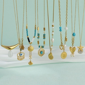 Close-up of 18K gold-plated stainless steel necklaces with turquoise and shell charms