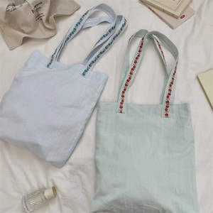 Détail de la broderie florale sur les anses du sac cabas en toile avec texture souple