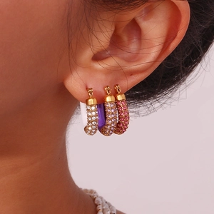 Close-up of gold U-shaped earrings with colorful pave zircon stones worn by a model
