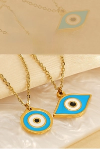 Macro shot of two gold evil eye pendants with blue enamel on a soft silk background