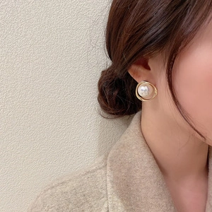 Close-up of elegant gold sunburst earrings with pearl detail worn on a model ear