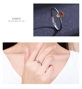 Detail view of oval gradient watermelon tourmaline ring in silver on finger and dark background