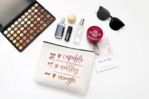 Flat lay of linen makeup bag with motivational print among cosmetics and accessories