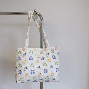 Detail of quilted cotton tote bag featuring colorful cartoon girl print and woven label