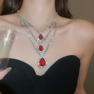 Dettaglio della collana argentata con tre pendenti rossi a goccia molto radiosi