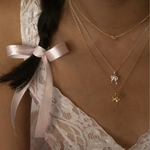Elegant layered bow necklaces in gold and silver finish on a model wearing white lace