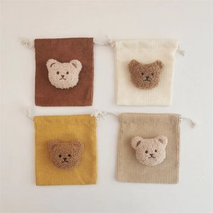 Corduroy drawstring storage pouches with plush bear decor in four assorted neutral colors