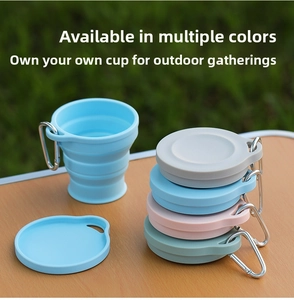 Detailed view of colorful collapsible silicone camping cups with metal carabiners on wood table