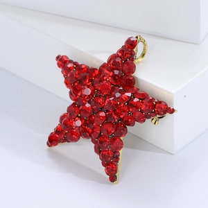 Detailed macro view of a vintage red crystal star brooch with gold setting on white stone