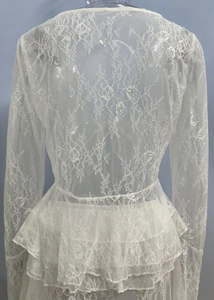 Dettaglio del top in pizzo bianco con balze in vita e delicate trame floreali trasparenti