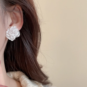 Detailed close-up of a white flower petal stud earring worn by a female model