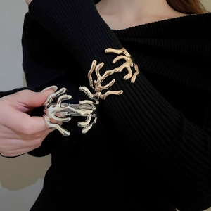 Artistic lava-style metal bracelets in gold and silver finish shown on a black sweater
