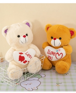 Close-up of cream and golden teddy bears with Love hearts on a plaid tablecloth