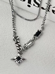 Detail view of silver layered chain necklace with star pendant and black gemstones