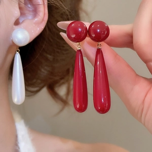 Close-up of elegant teardrop earrings in vintage red and ivory with gold accents